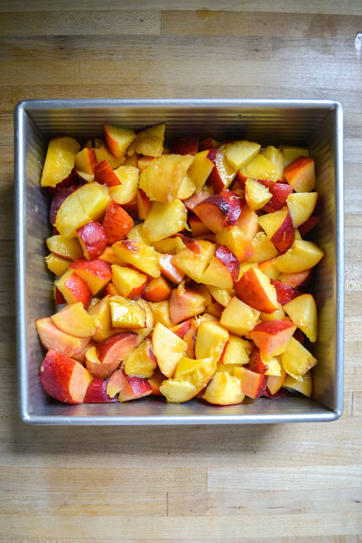 Chopped peaches in a square baking dish.