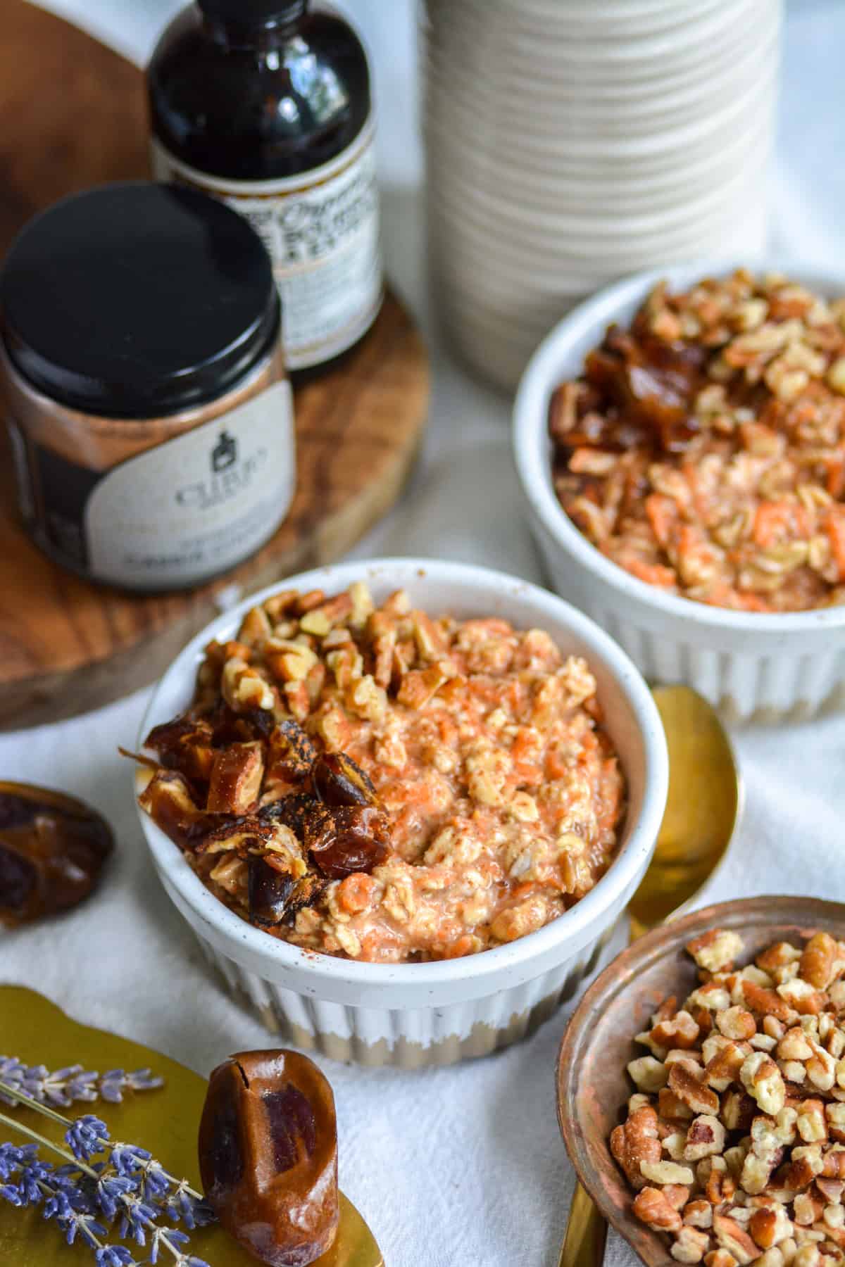 Carrot Cake Overnight Oatmeal in a white ramekin topped with chopped dates and pecans.