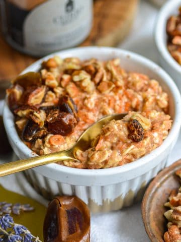 Carrot Cake Overnight Oats in a white ramekin with a gold spoon in it.
