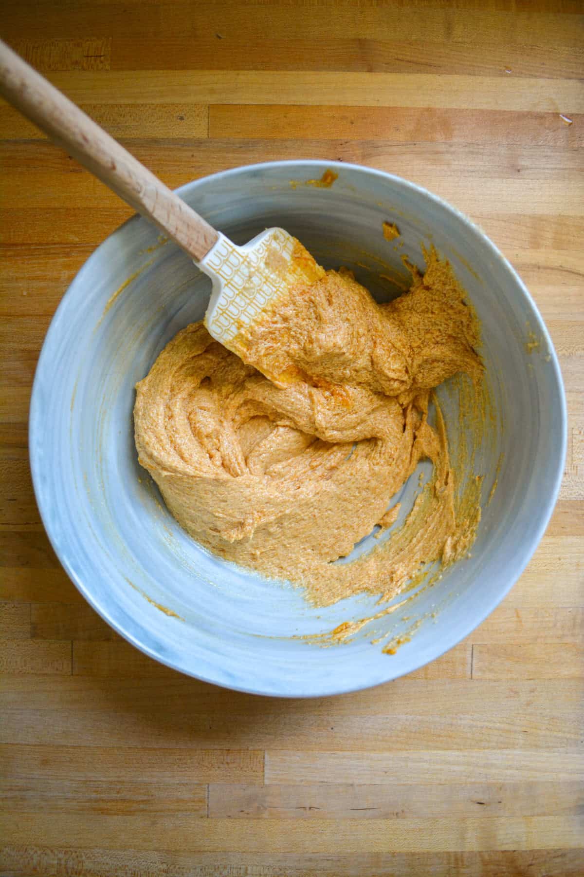 Butter and brown sugar creamed in a large mixing bowl with a spatula in it.