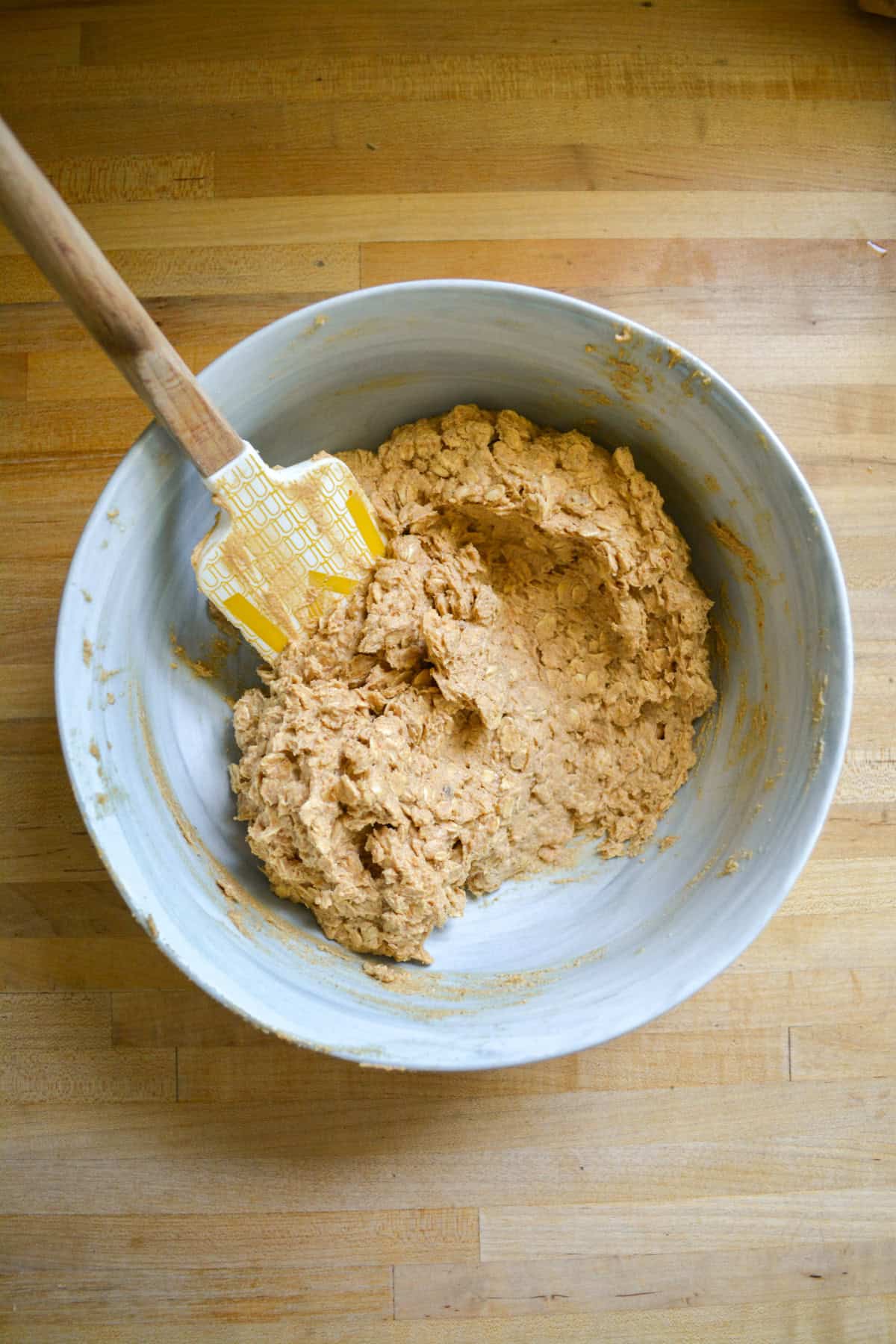 Cookie dough in a mixing bowl with a spatula in it.