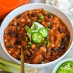 A bowl of Vegetarian Three Bean Chili topped with sour cream and slices of jalapeño.