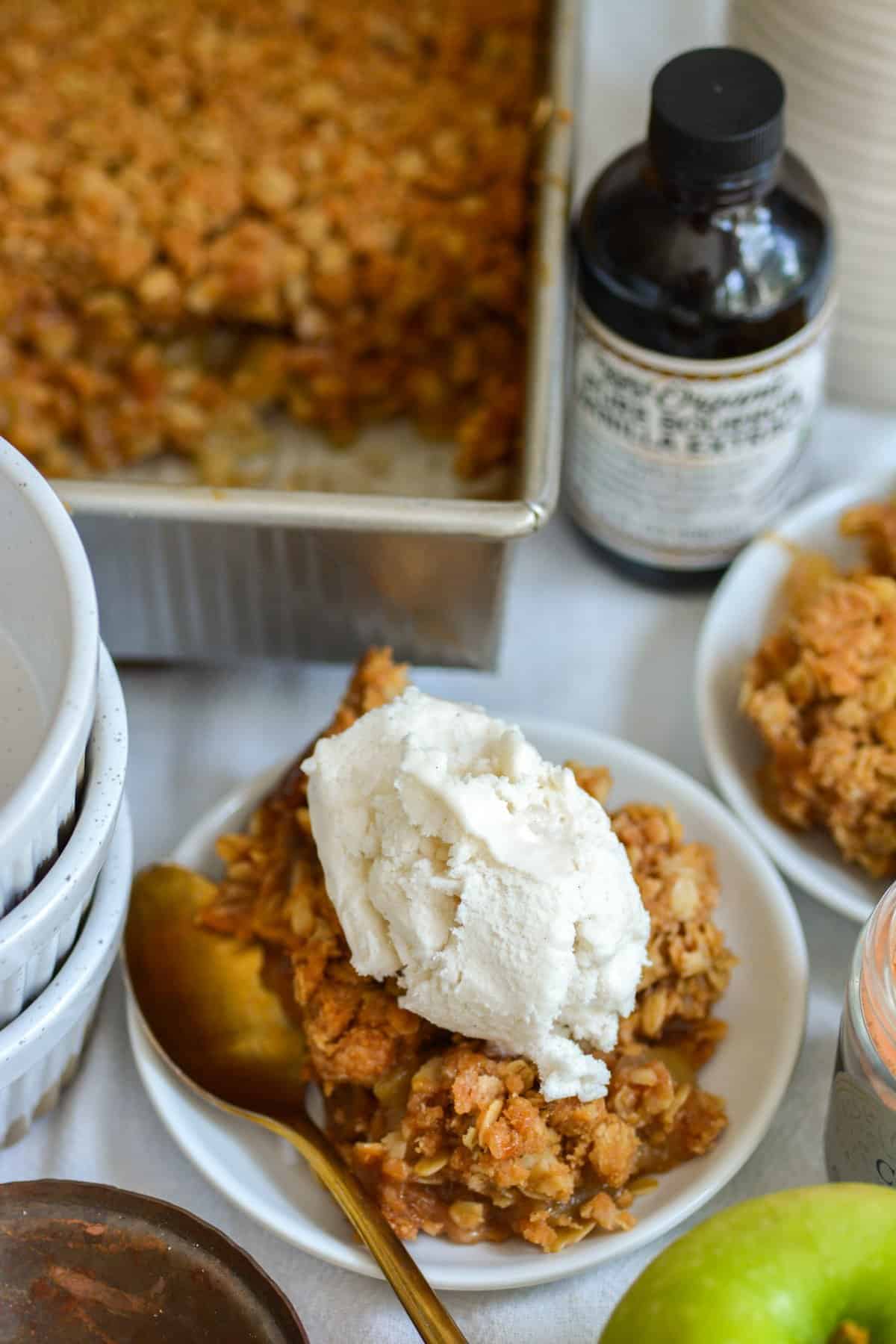 Vegan Apple Crumble topped with a scoop of ice cream on a small plate.