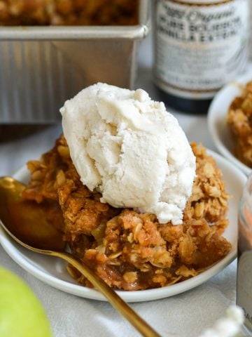 A small plate with Vegan Apple Crumble topped with ice cream.
