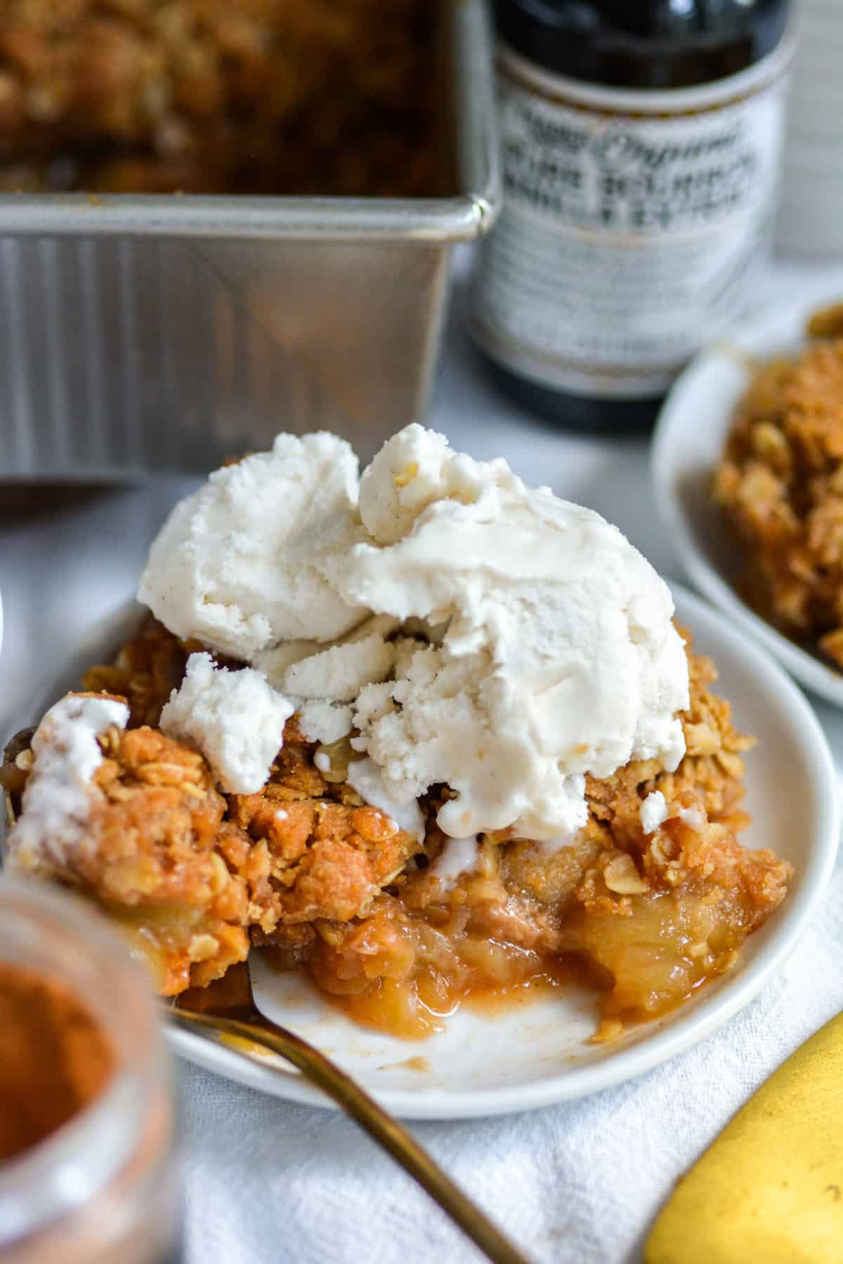 A bite taken out of vegan apple crumble on a plate.