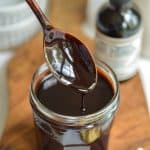 A spoon with vegan chocolate sauce dripping off of it.