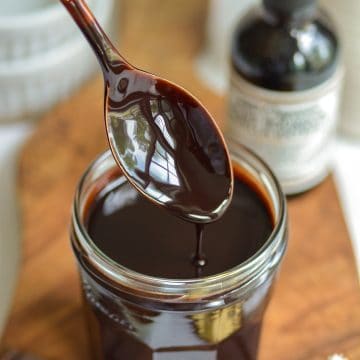 A spoon with vegan chocolate sauce dripping off of it.