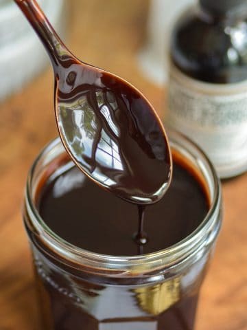 A spoon with vegan chocolate sauce dripping off of it.