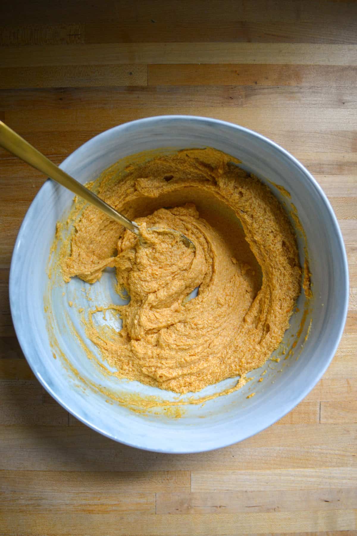 Pumpkin added to the creamed mixture in a large mixing bowl.