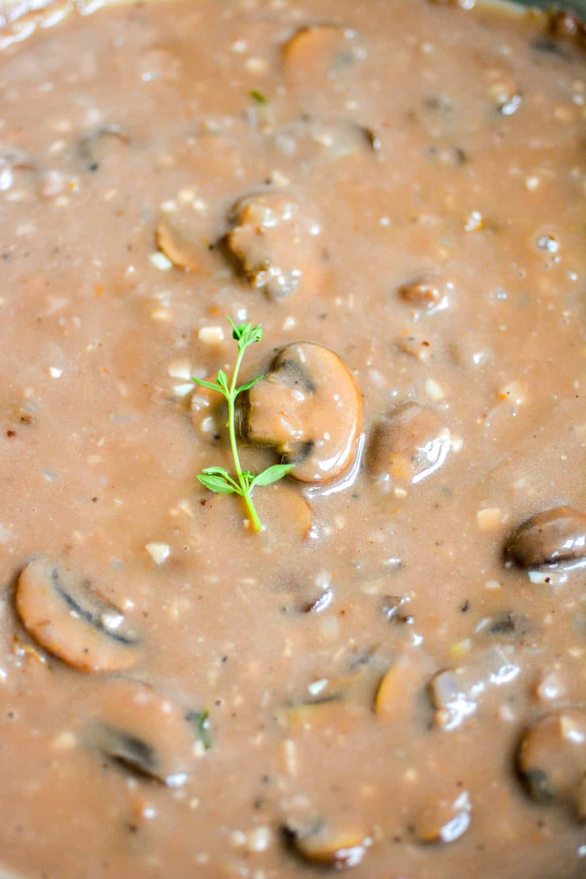 Vegan Mushrooms Gravy in a skillet topped with a sprig of thyme.