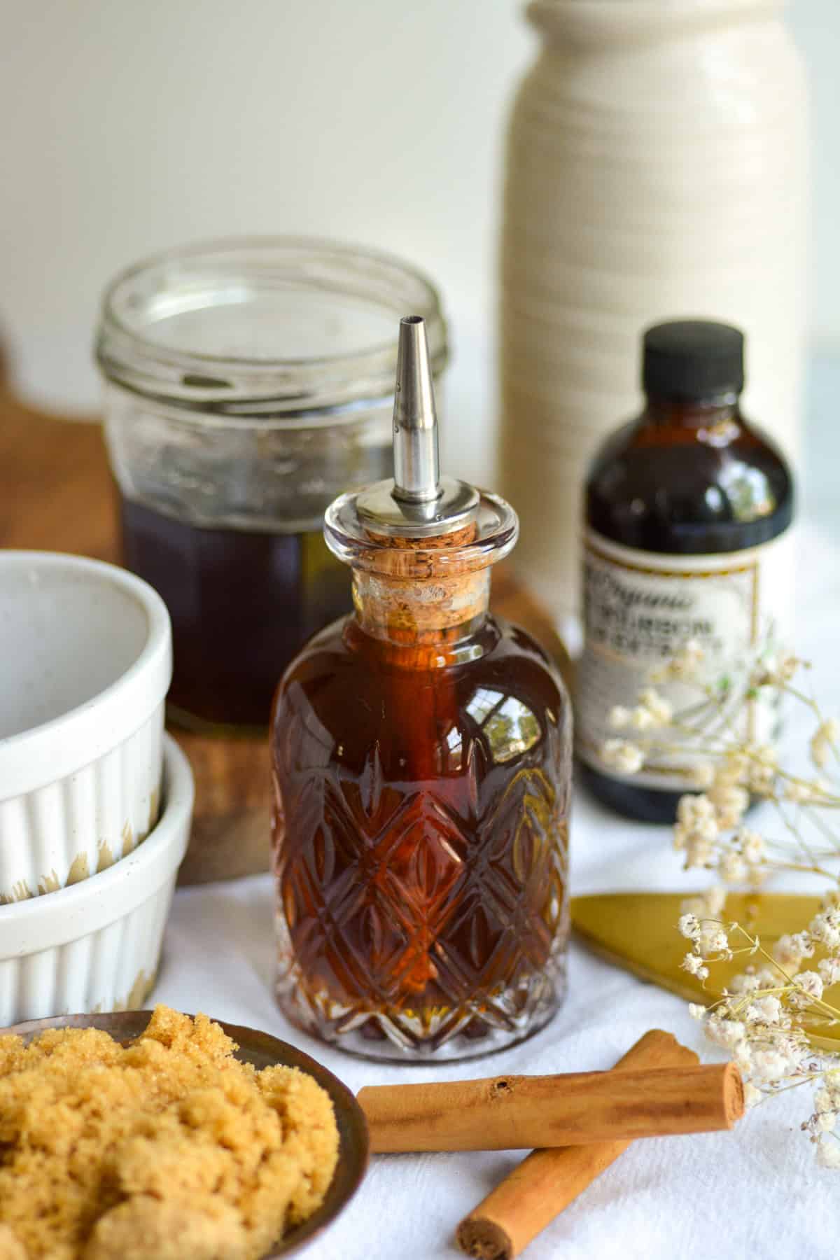A bottle of Brown Sugar Simple Syrup with 2 cinnamon sticks in front of it.