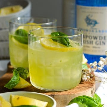 Gin Basil Smash in a glass topped with a lemon wheel and fresh basil.