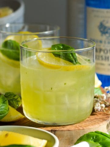 Gin Basil Smash in a glass topped with a lemon wheel and fresh basil.