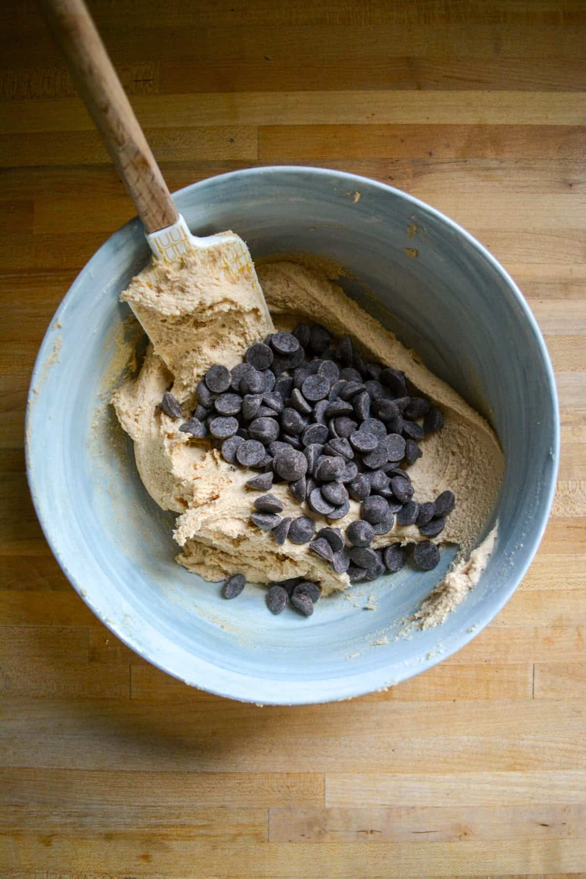 Gluten free cookie dough with chocolate chips added into it in a large bowl.