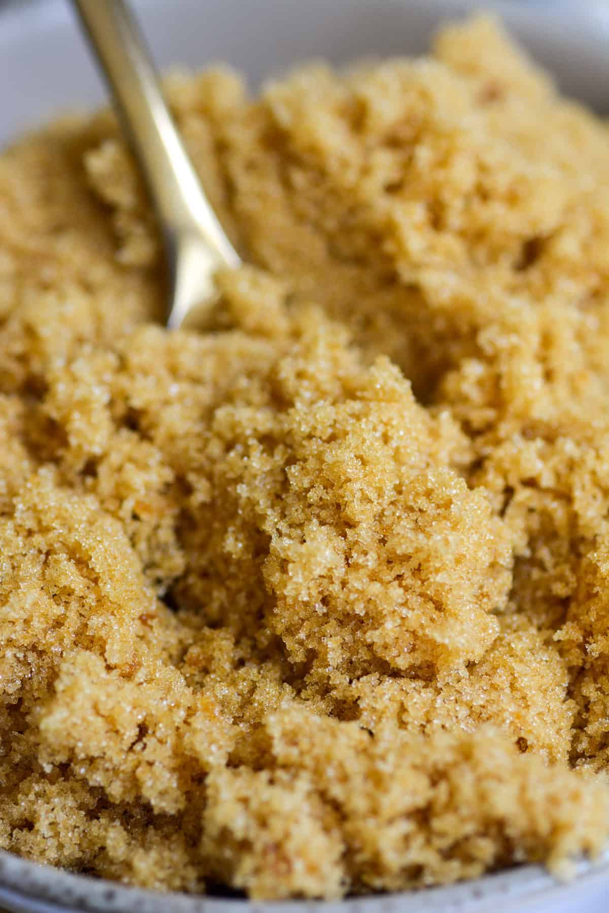 Homemade light brown sugar on a gold spoon.