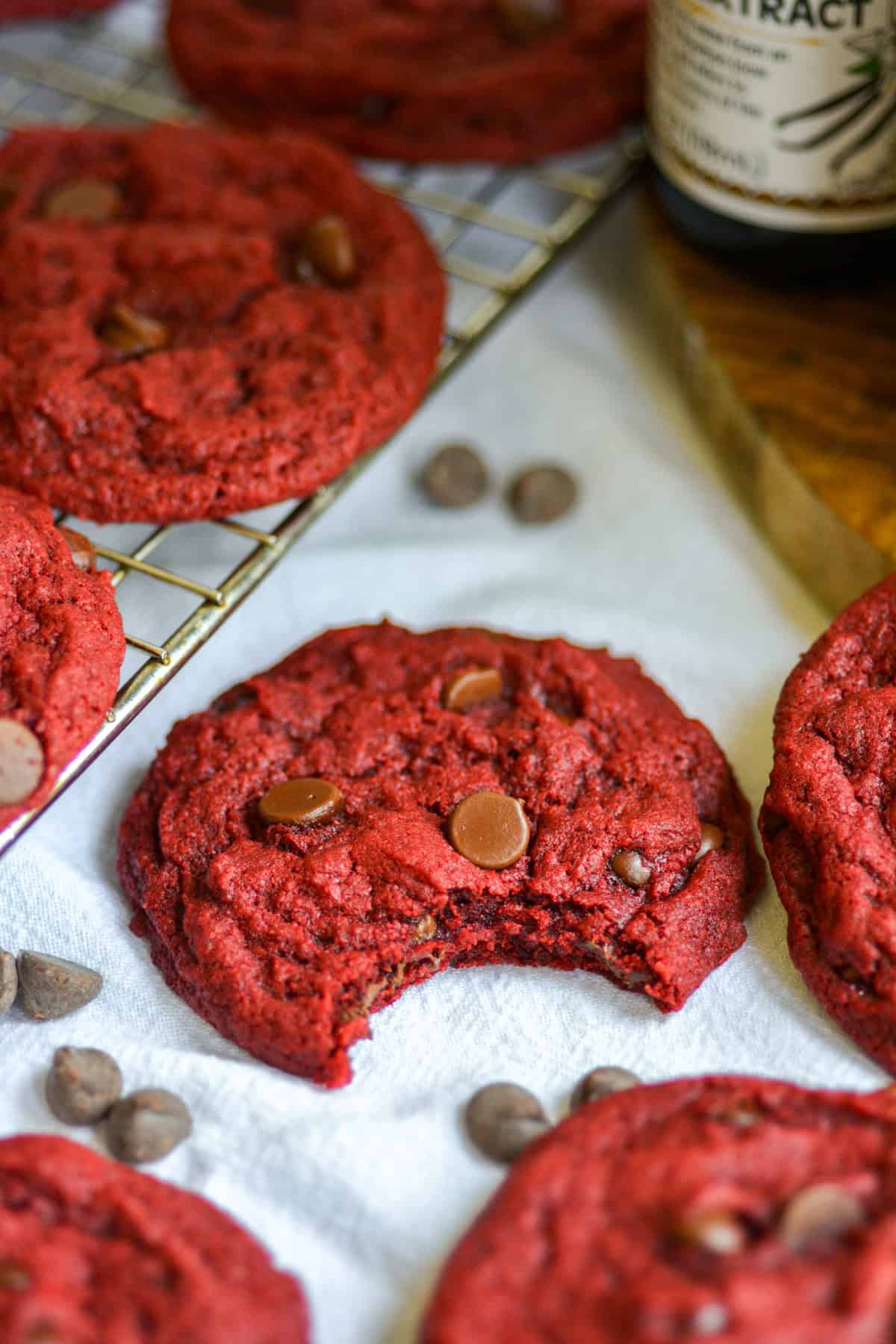 A red velvet chocolate chip cookie with a bite taken out of it on a linen cloth.