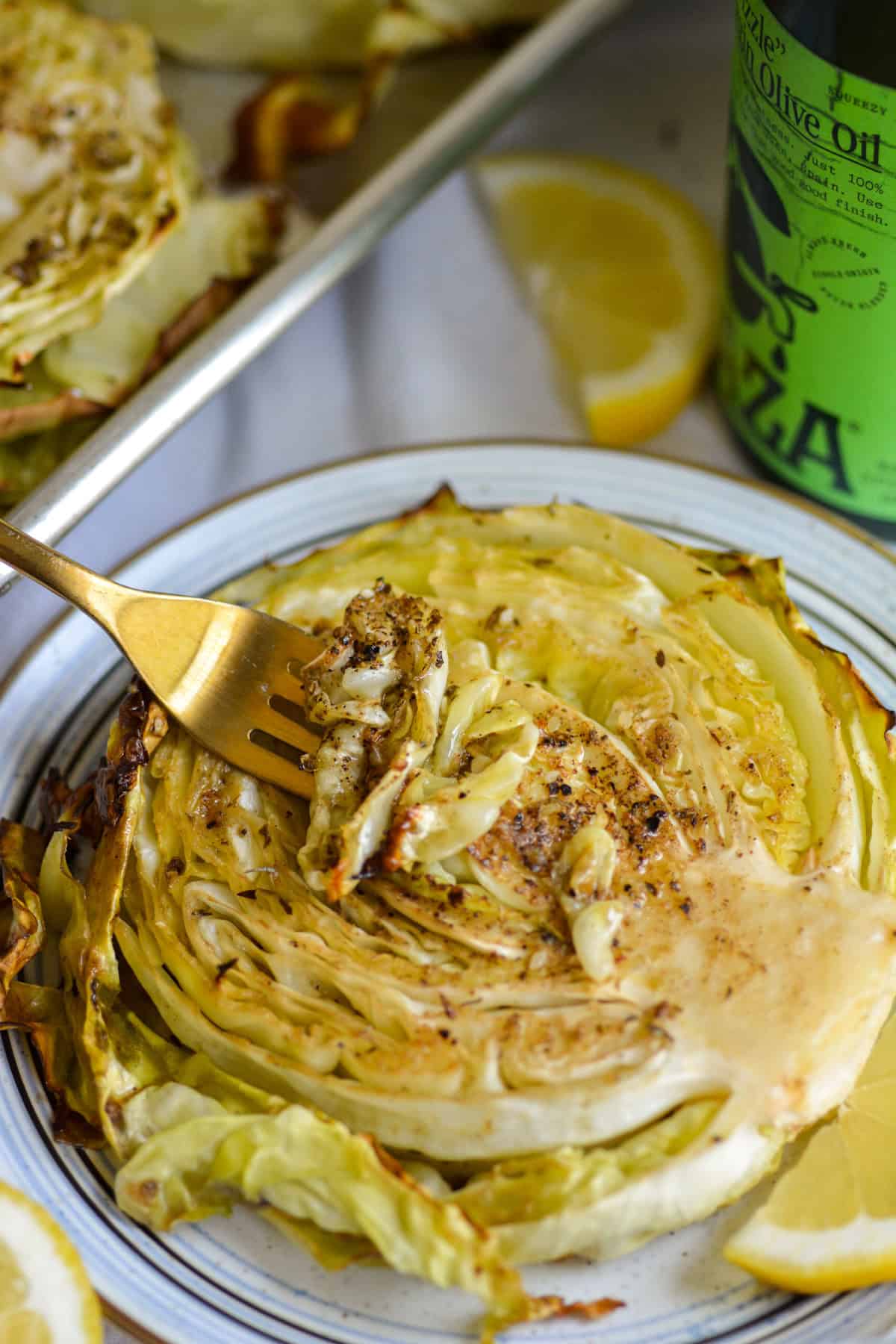 A fork with a bite of roasted cabbage steak on it.
