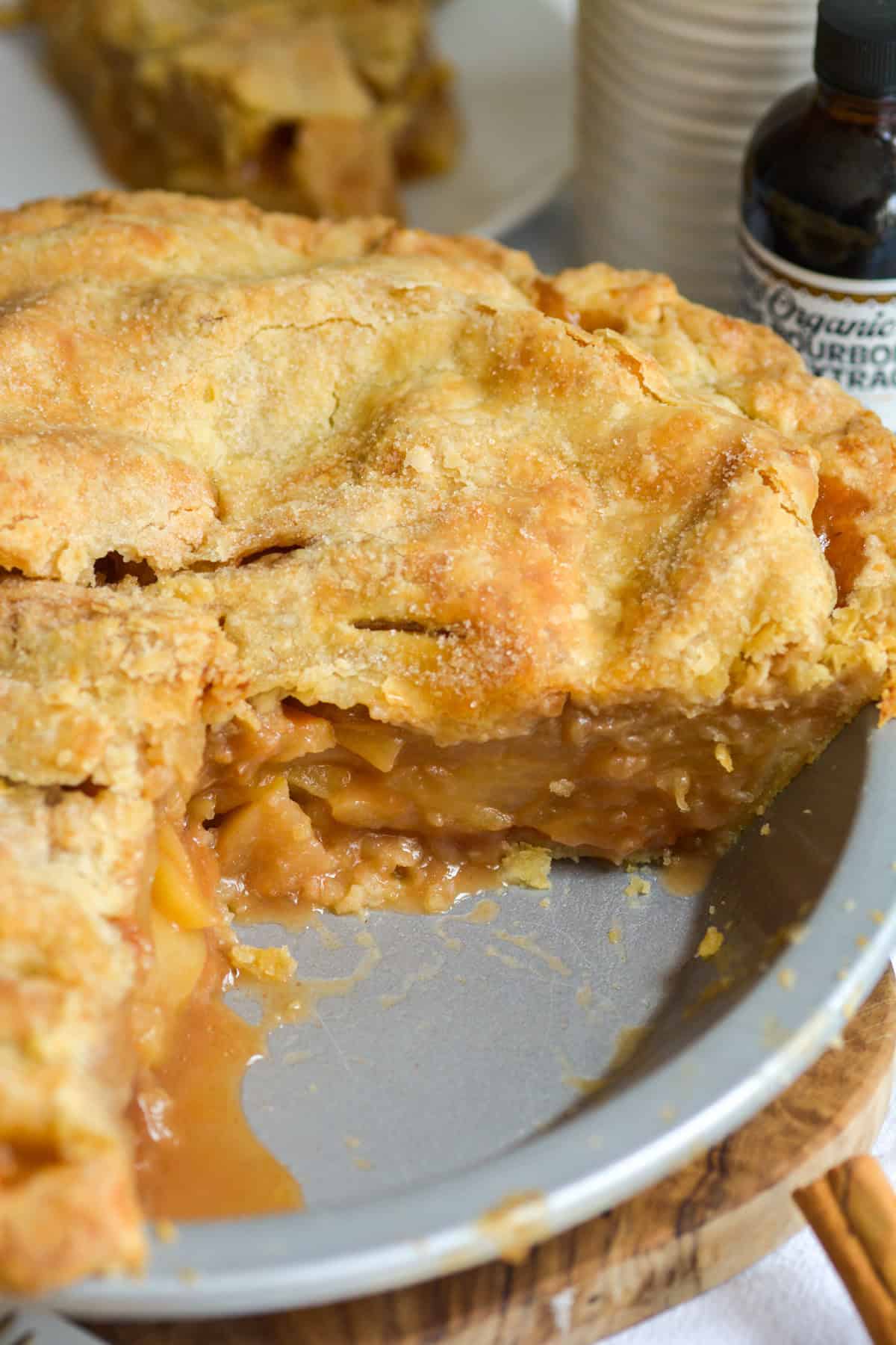 An homemade Vegan Apple Pie in a pie plate with a slice taken out of it.