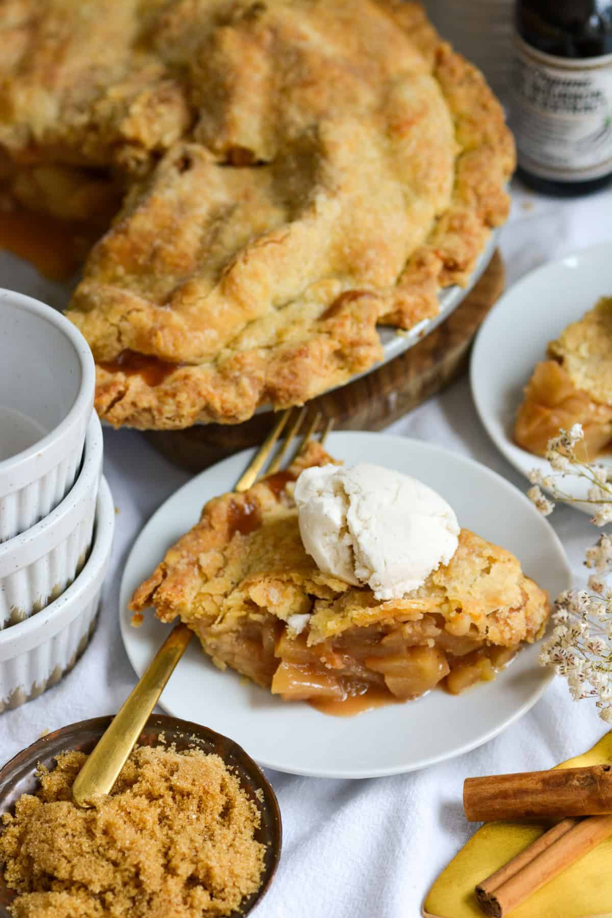 A slice of homemade Vegan Apple Pie on a small plate topped with a scoop of ice cream.