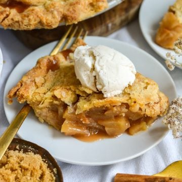 A slice of homemade Vegan Apple Pie topped with ice cream on a small plate.