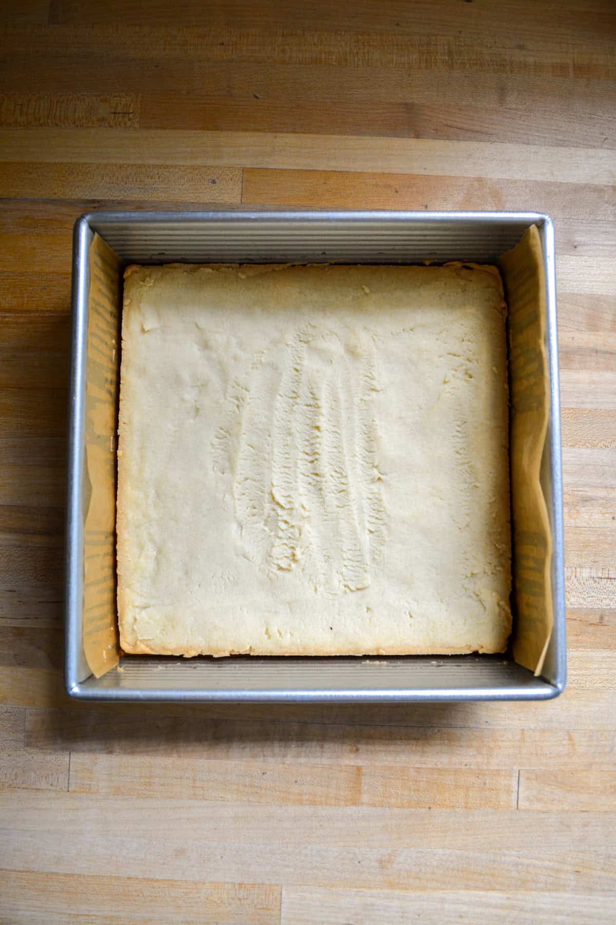 Baked shortbread crust in a square pan.