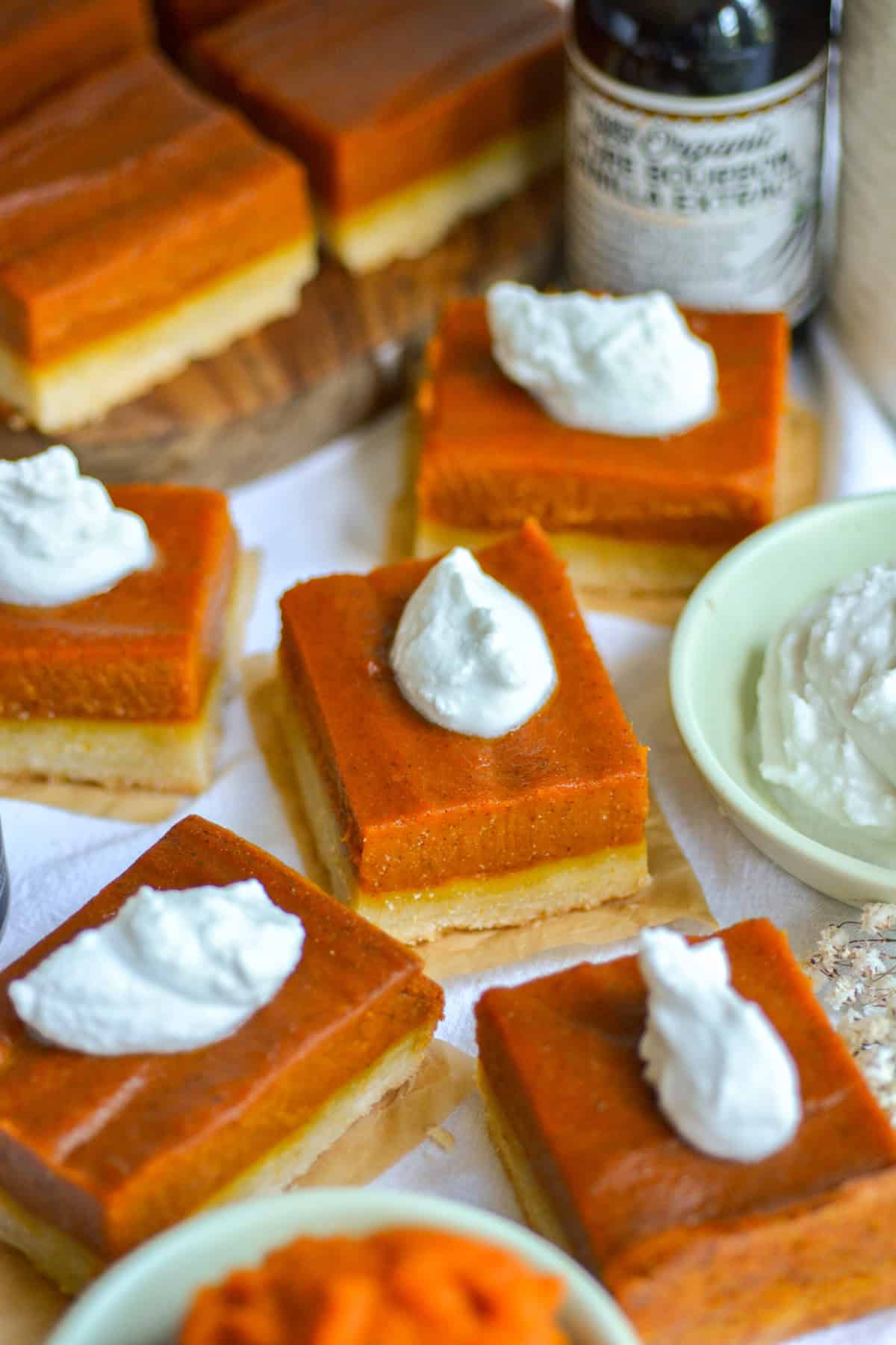 Pumpkin Pie Bars topped with whipped cream on a linen cloth.