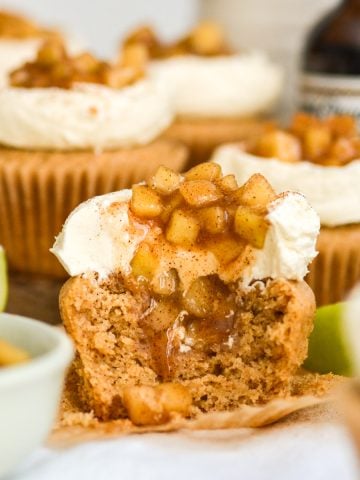 A Vegan Spiced Apple Pie Cupcake with a bite taken out of it to show the cener.