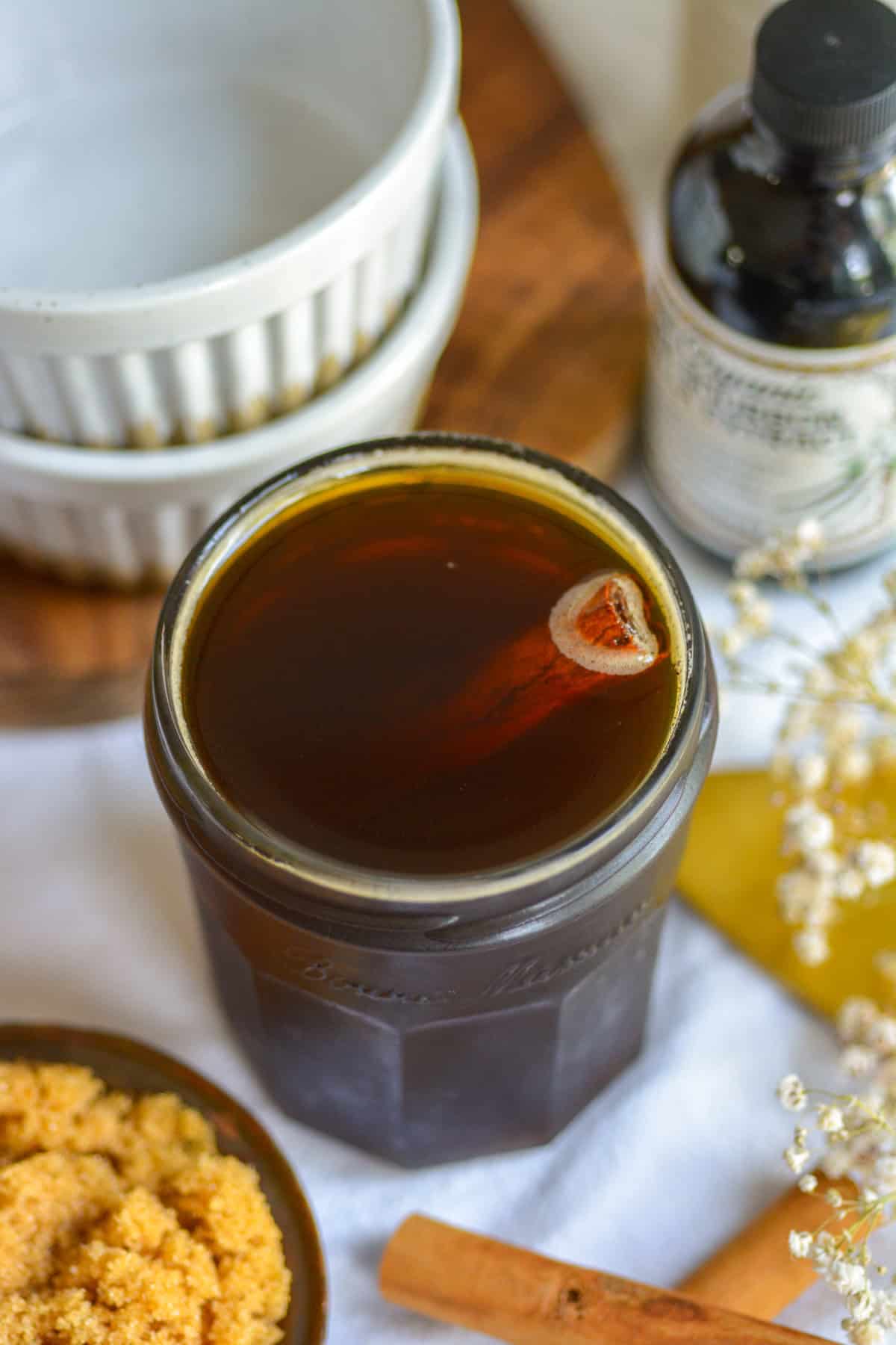 Brown sugar syrup in a glass jar with a cinnamon stick inside it.