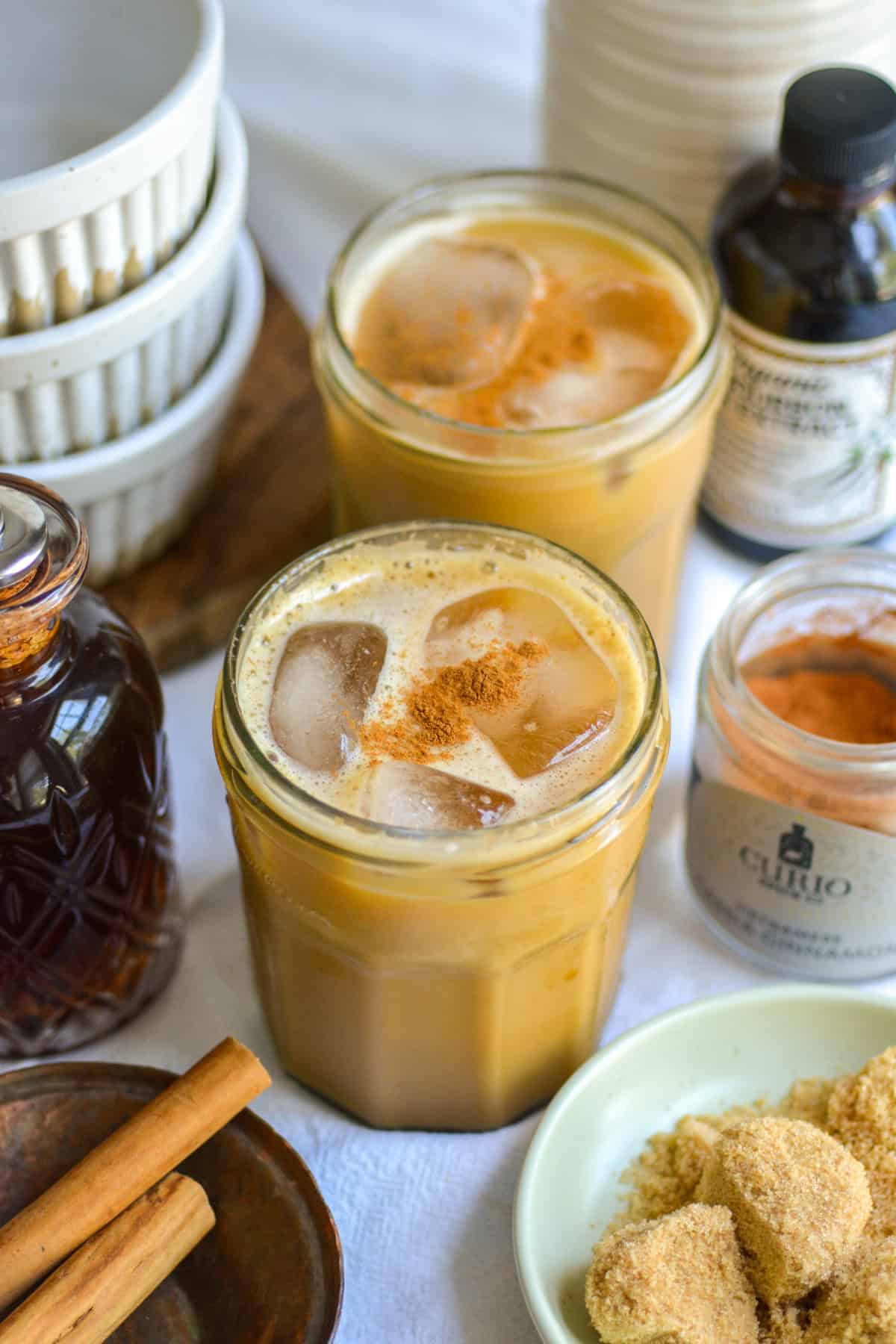 Two glasses of Iced Brown Sugar Oat Milk Shaken Espresso on a linen cloth.