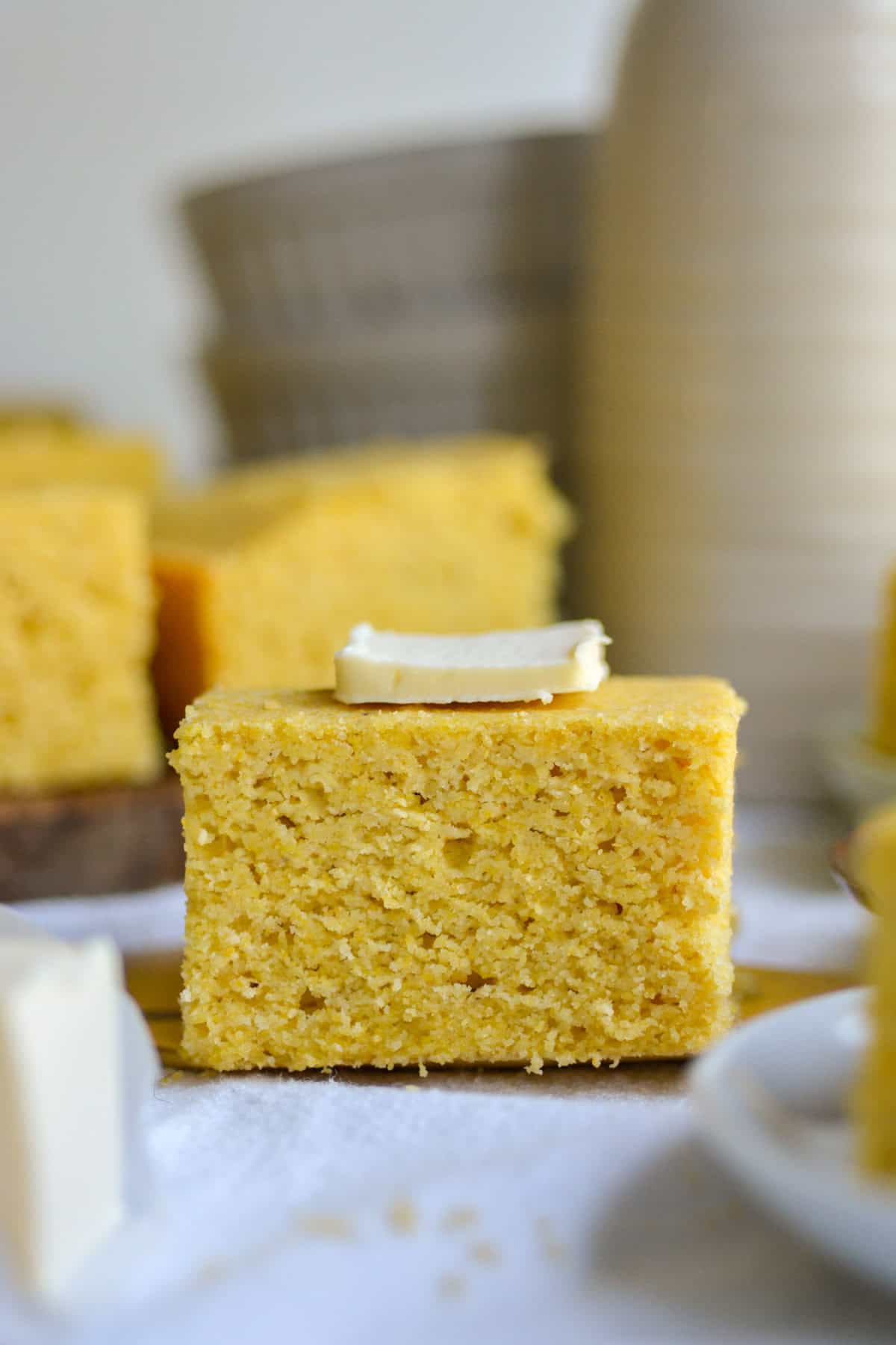 Photo of the side of a piece of Vegan Cornbread topped with a pat of butter.