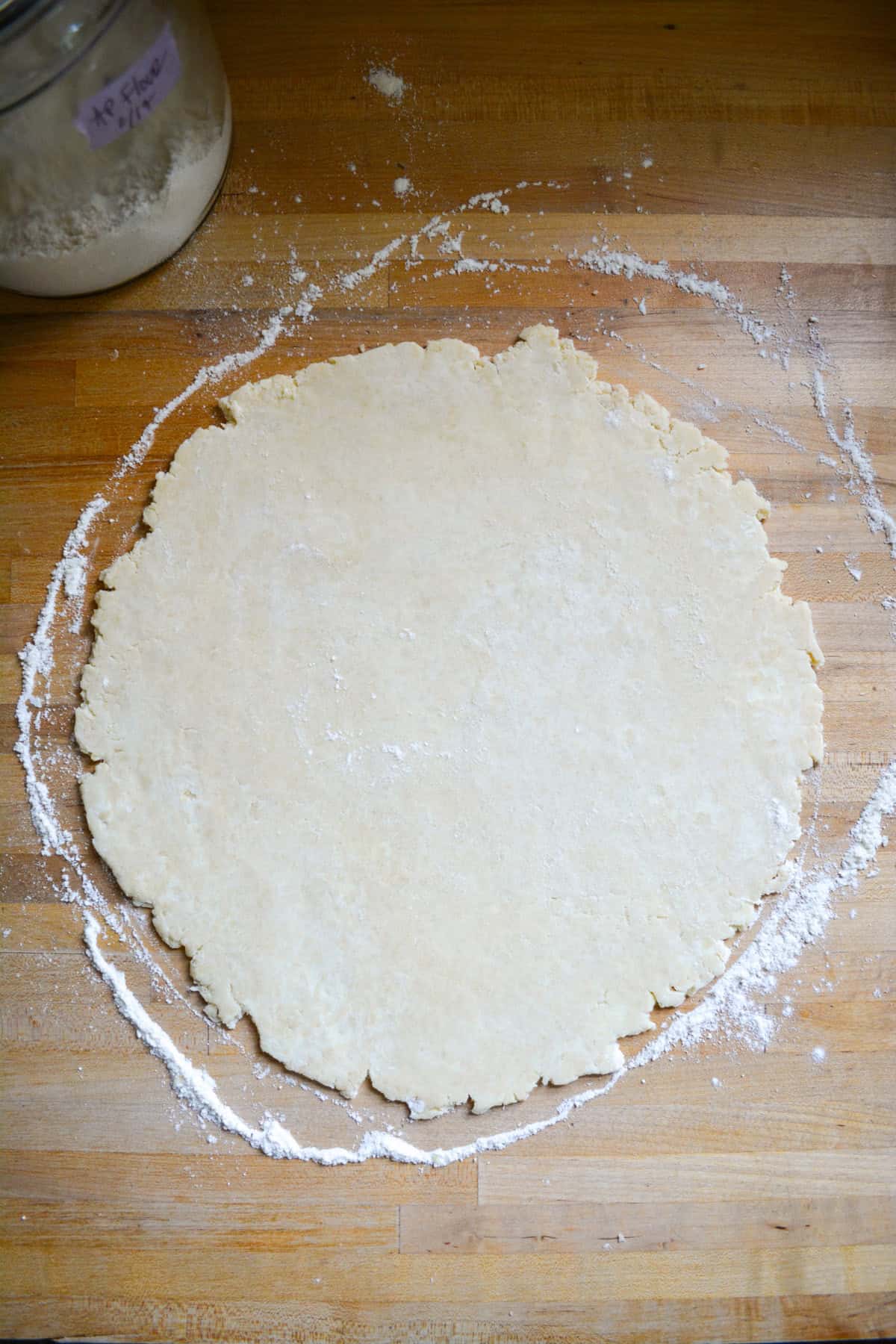 Pie dough rolled into a circle on a wooden surface.