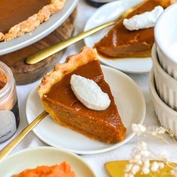 A slice of Vegan Pumpkin Pie with a dollop of whipped cream on a small white plate.