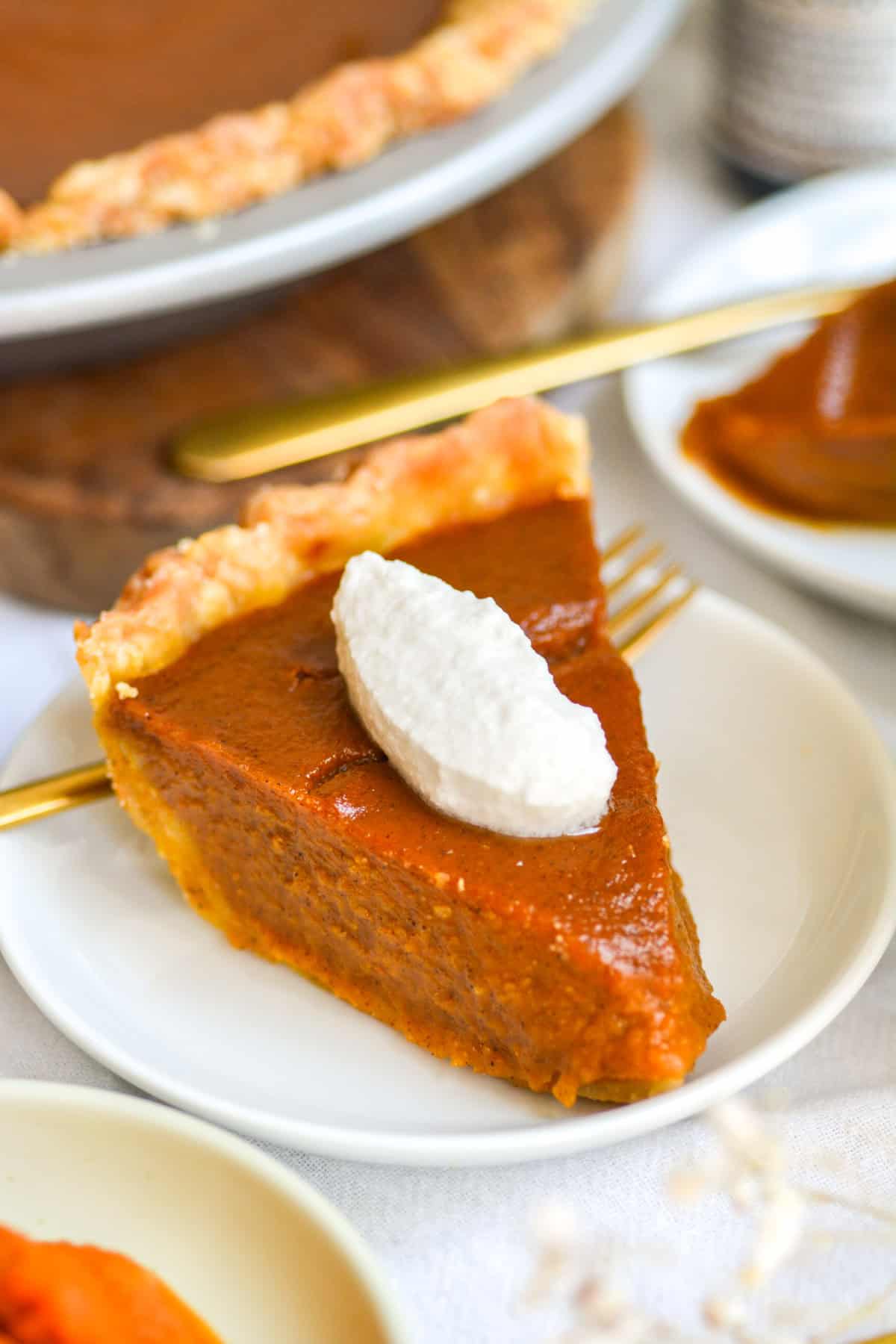 Vegan Pumpkin Pie on a small plate topped with whipped cream.