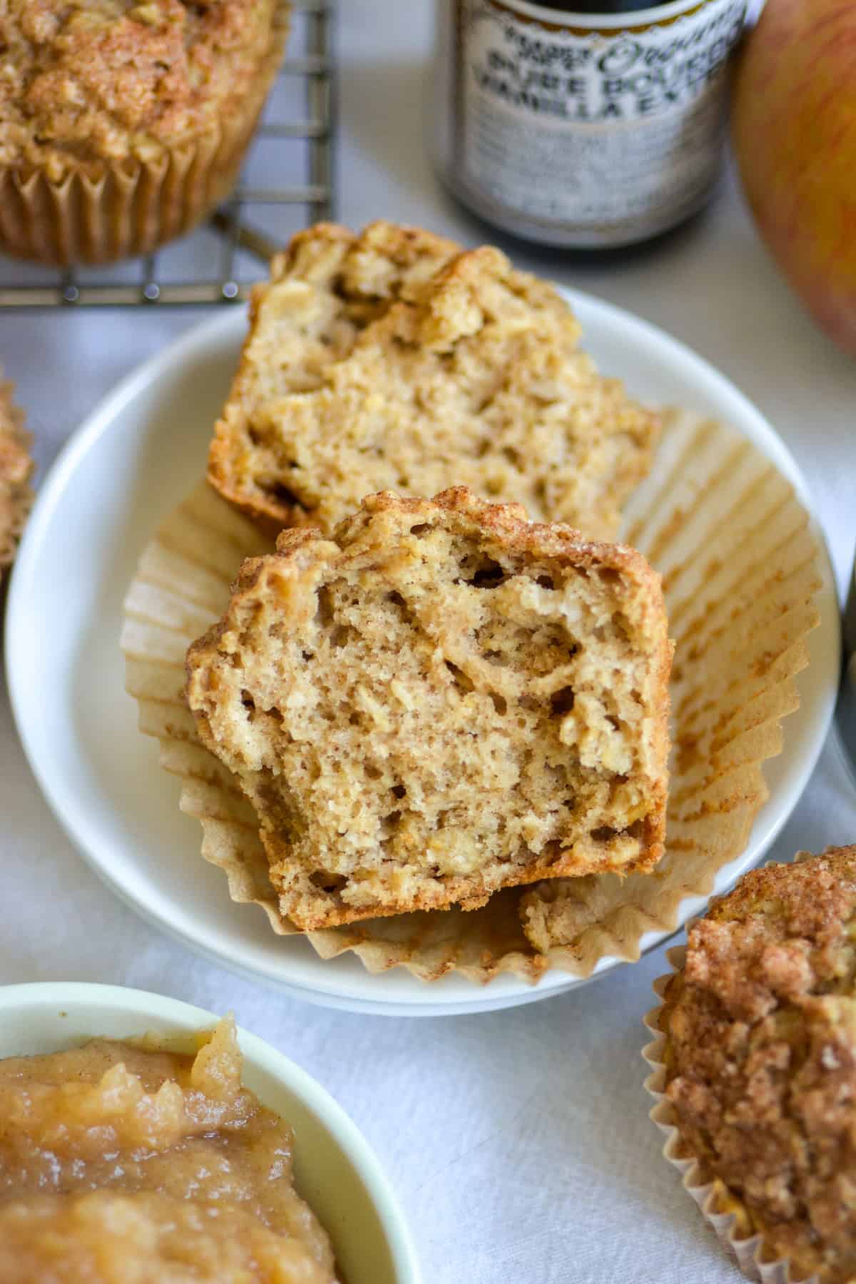 An Applesauce Oatmeal Muffin that is broken in half on a small white plate.