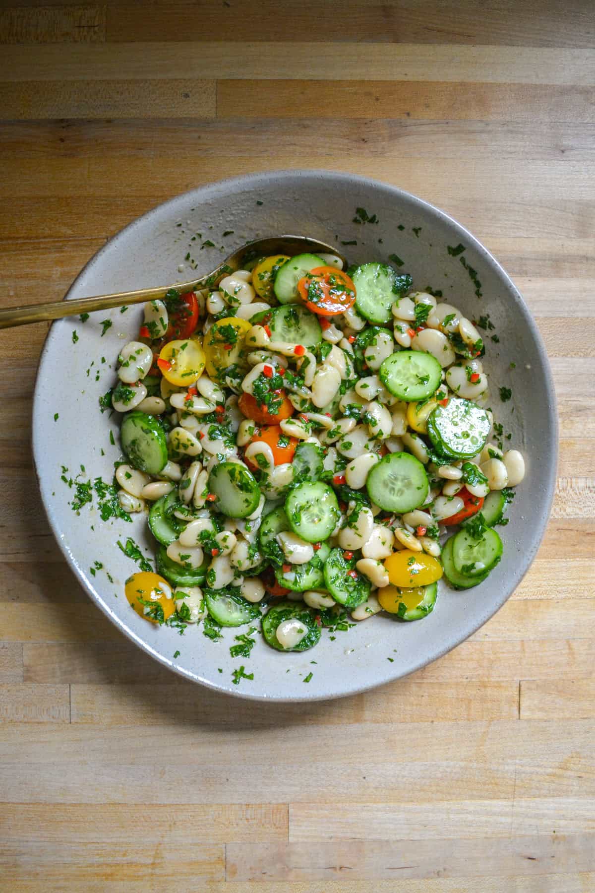 Sliced cucumbers, tomatoes and beans added to the vinaigrette and tossed together.