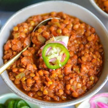 Lentil Chili in a bowl topped with sour cream and a jalapeno slice.