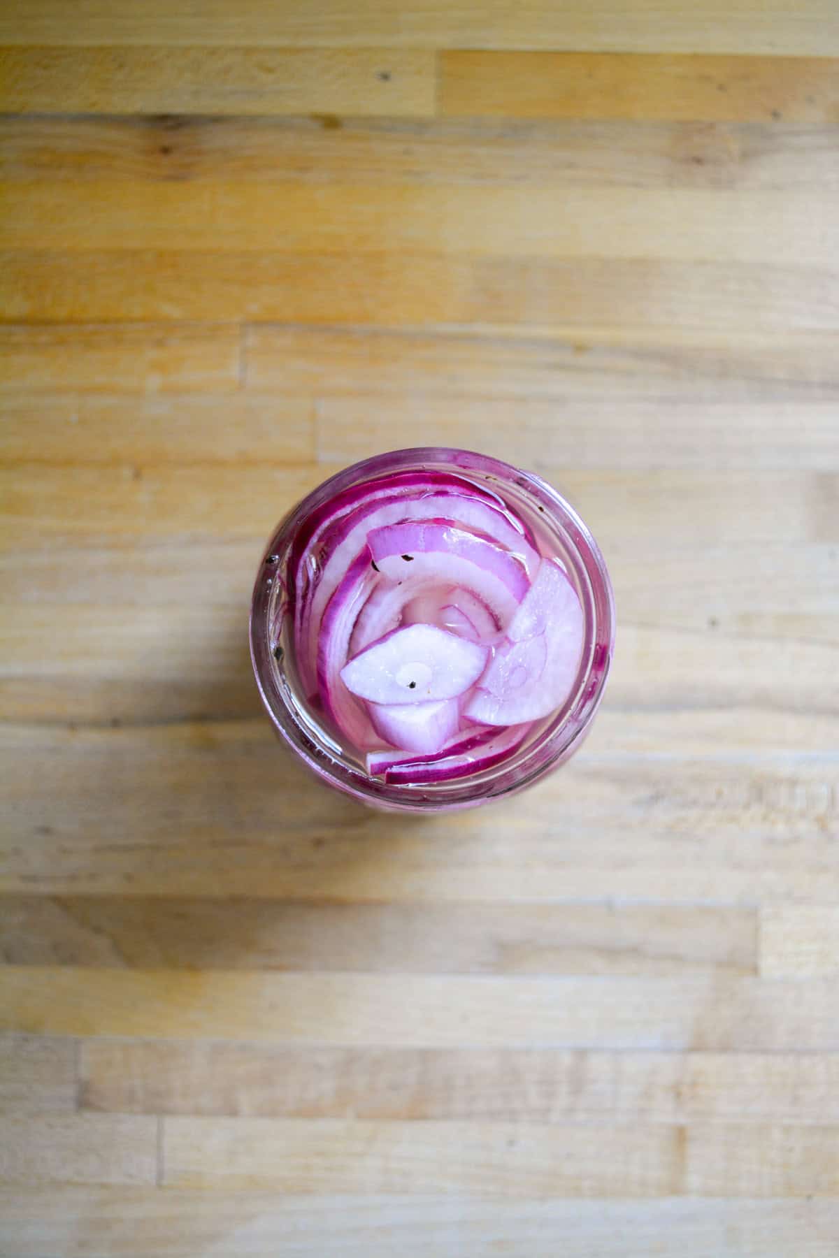 Sliced onions added to the brine in a jar.