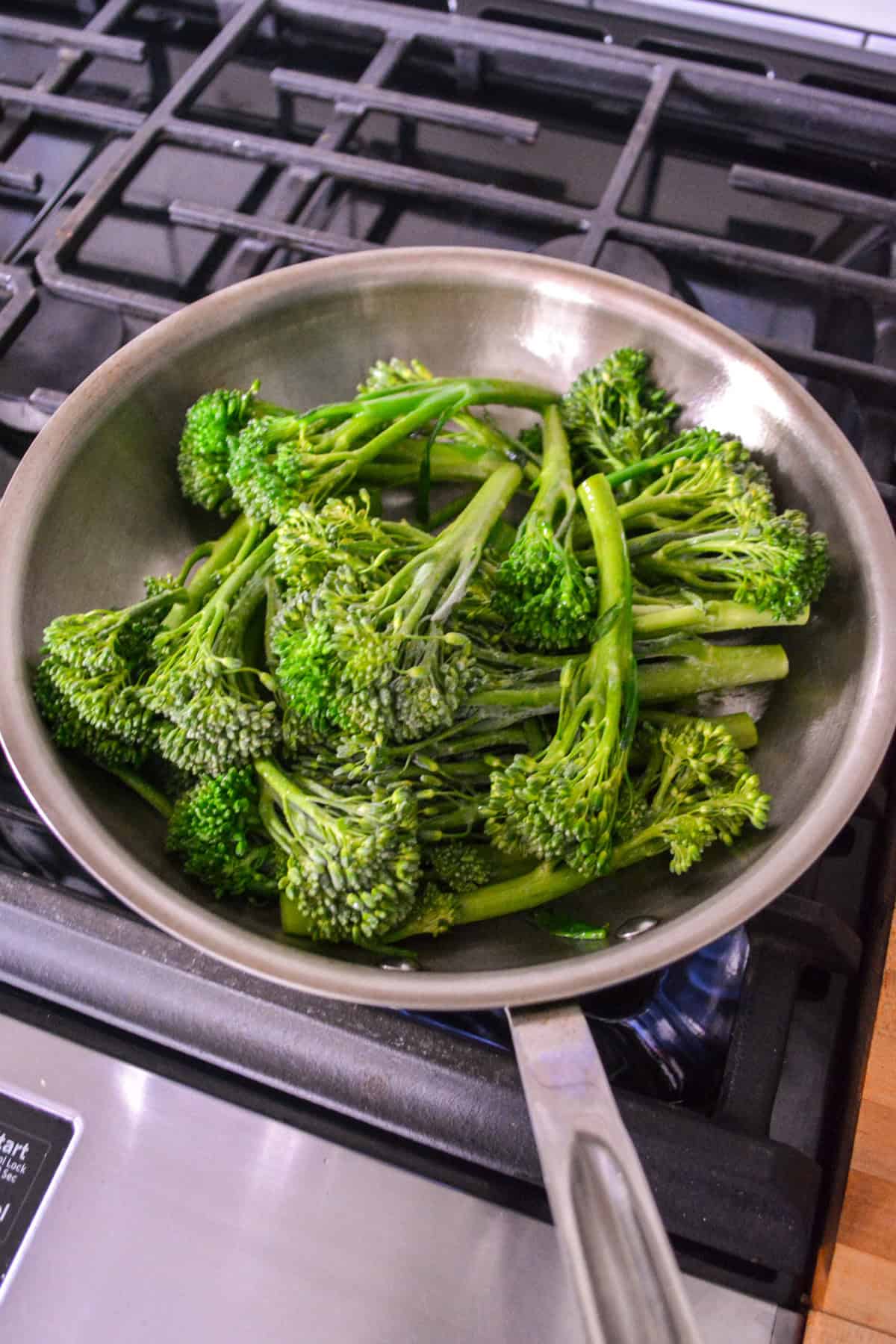 Broccolini in a large skillet on a stovetop.