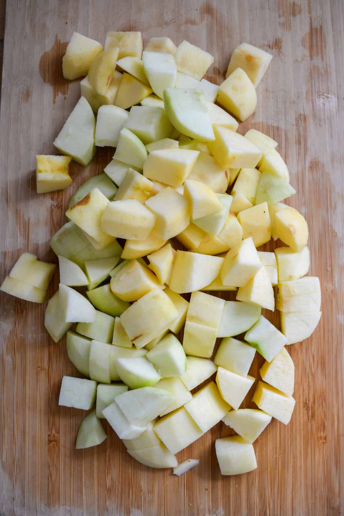 Peeled and chopped apples on a wooden cutting board.