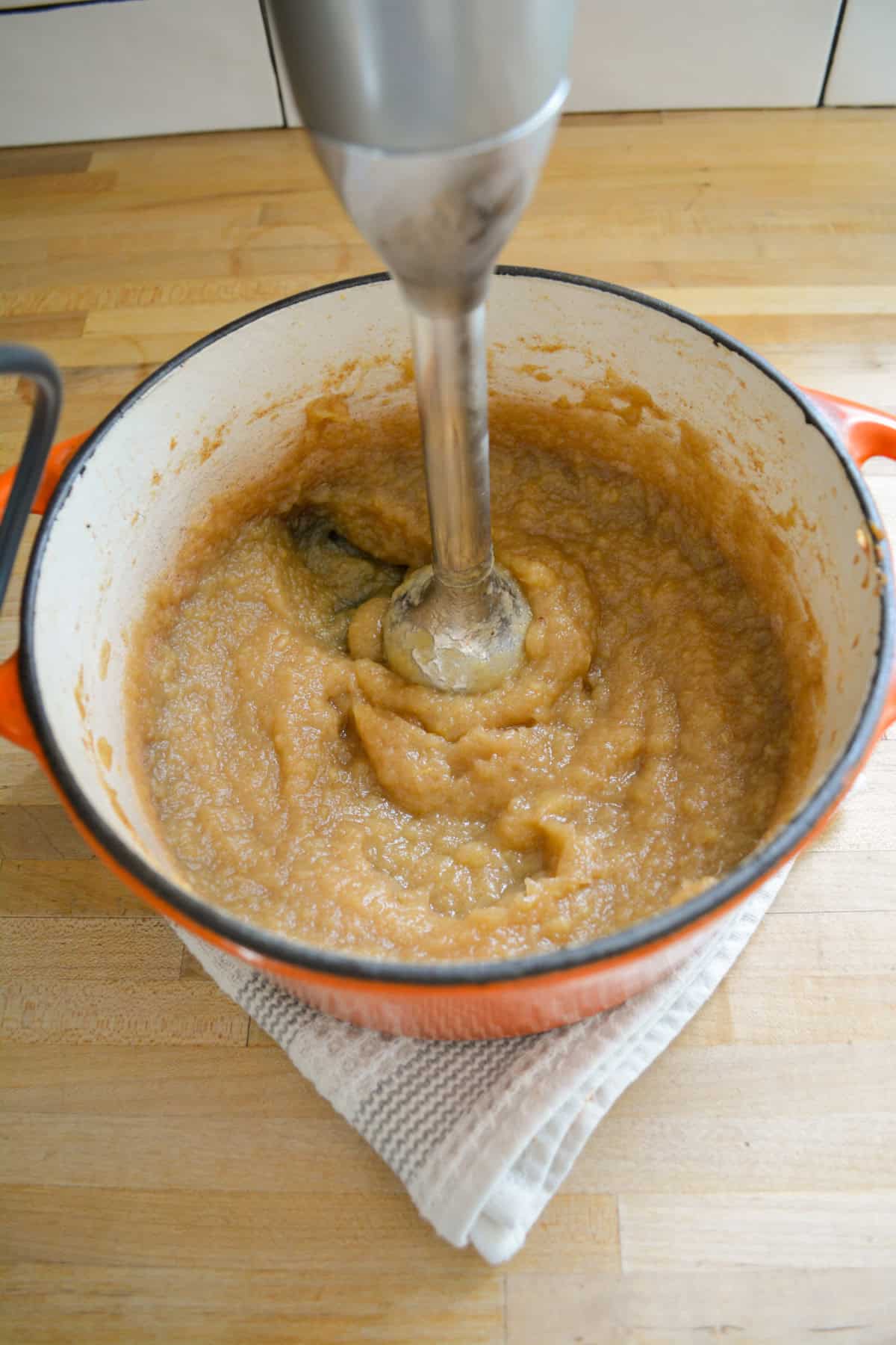Immersion blending applesauce in a Dutch oven.