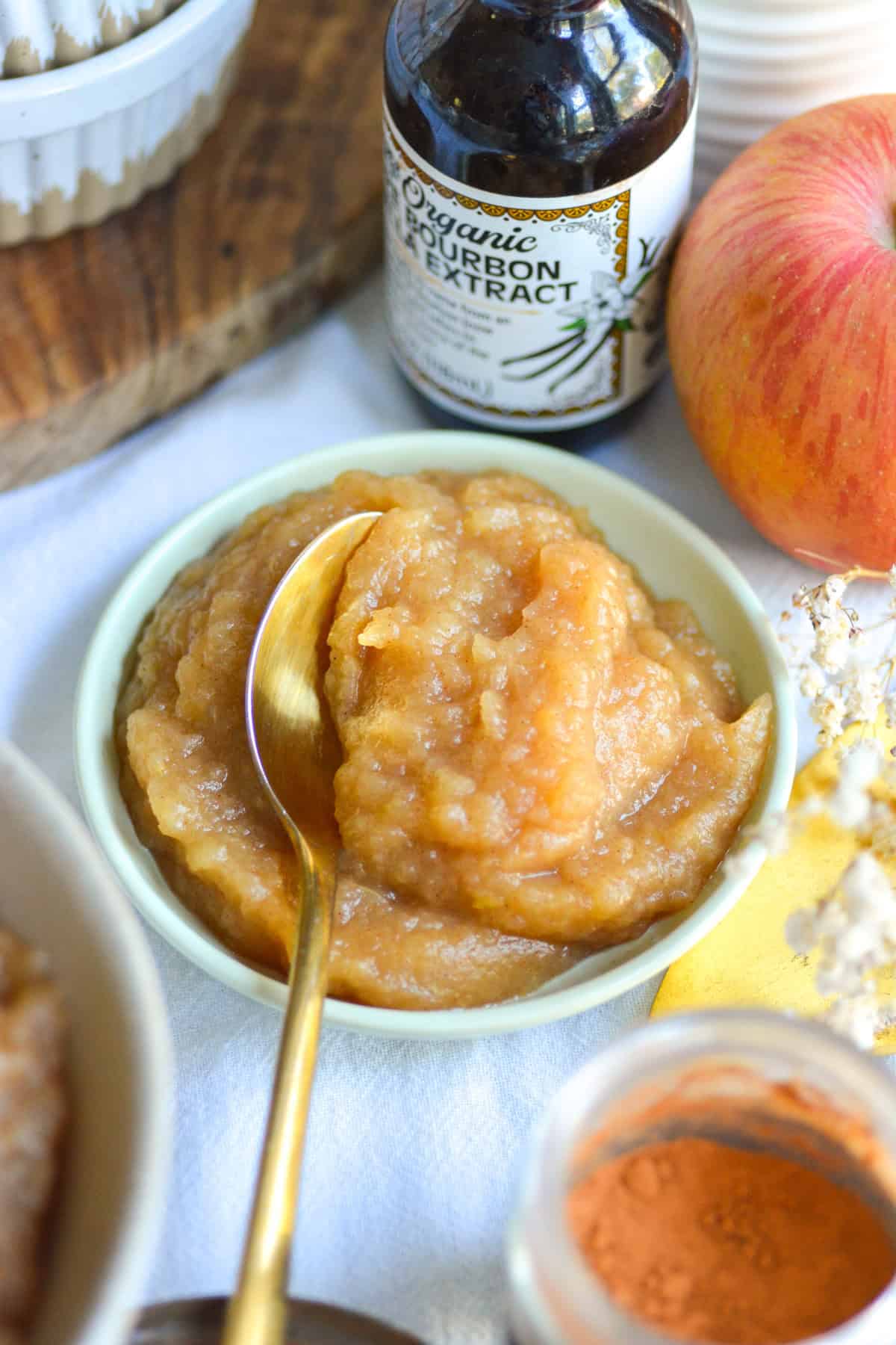 Unsweetened Applesauce in a small bowl with a gold spoon in it.