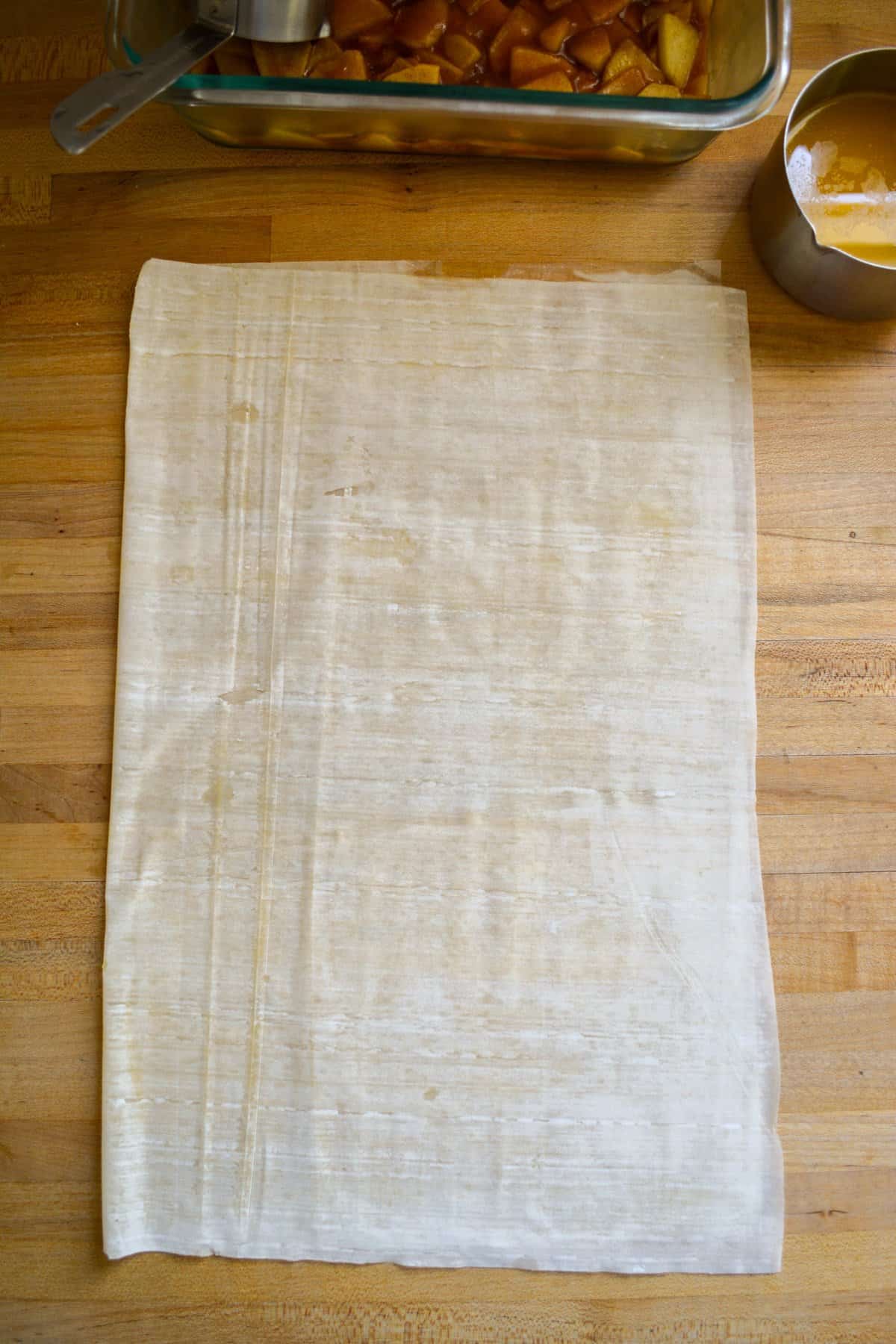 A phyllo dough sheet spread with melted butter and folded in half.