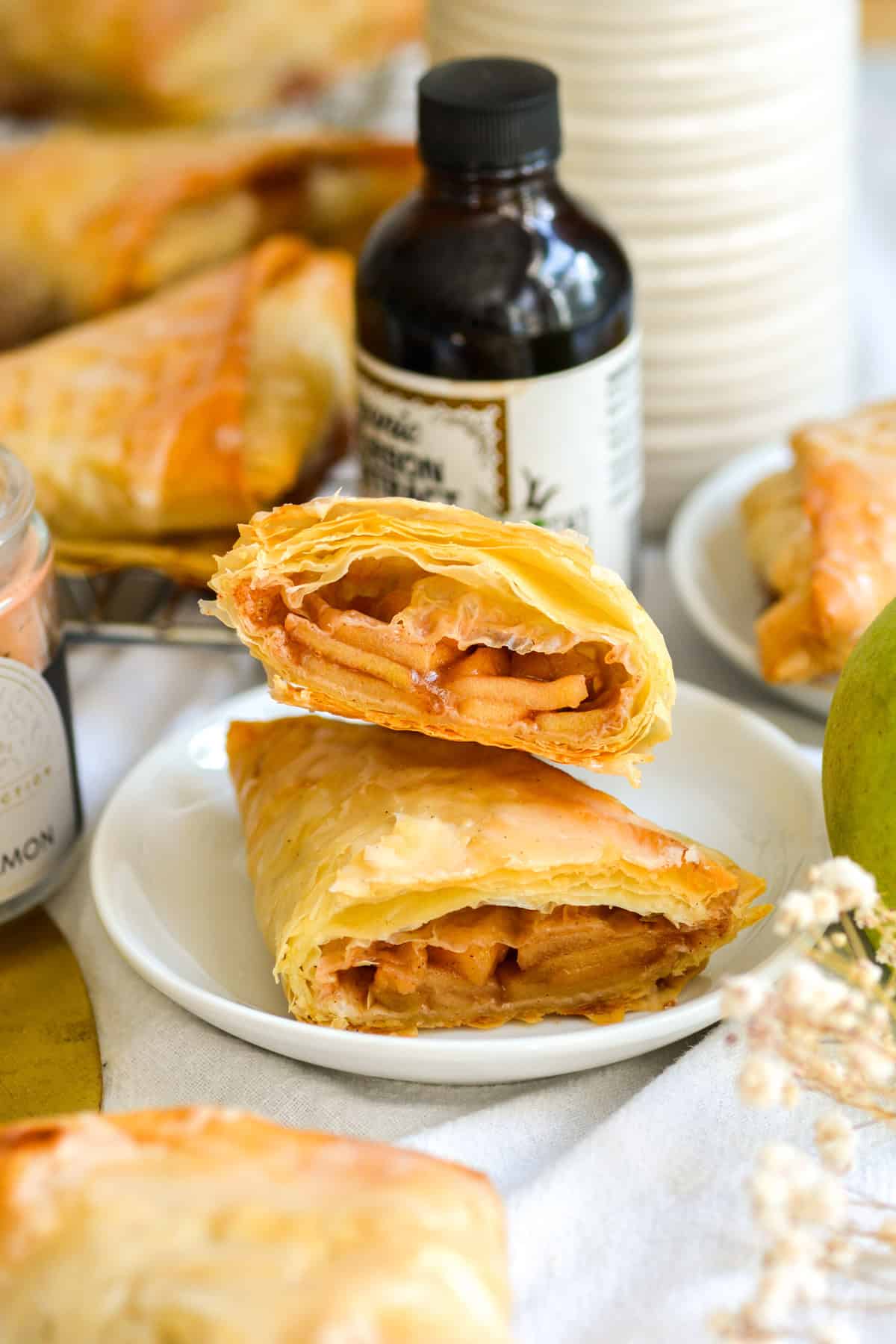 A vegan Apple Turnover cut in half on a small white plate.
