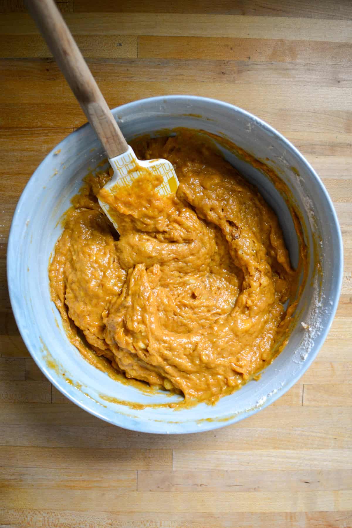 Batter in a large mixing bowl on a wooden surface.