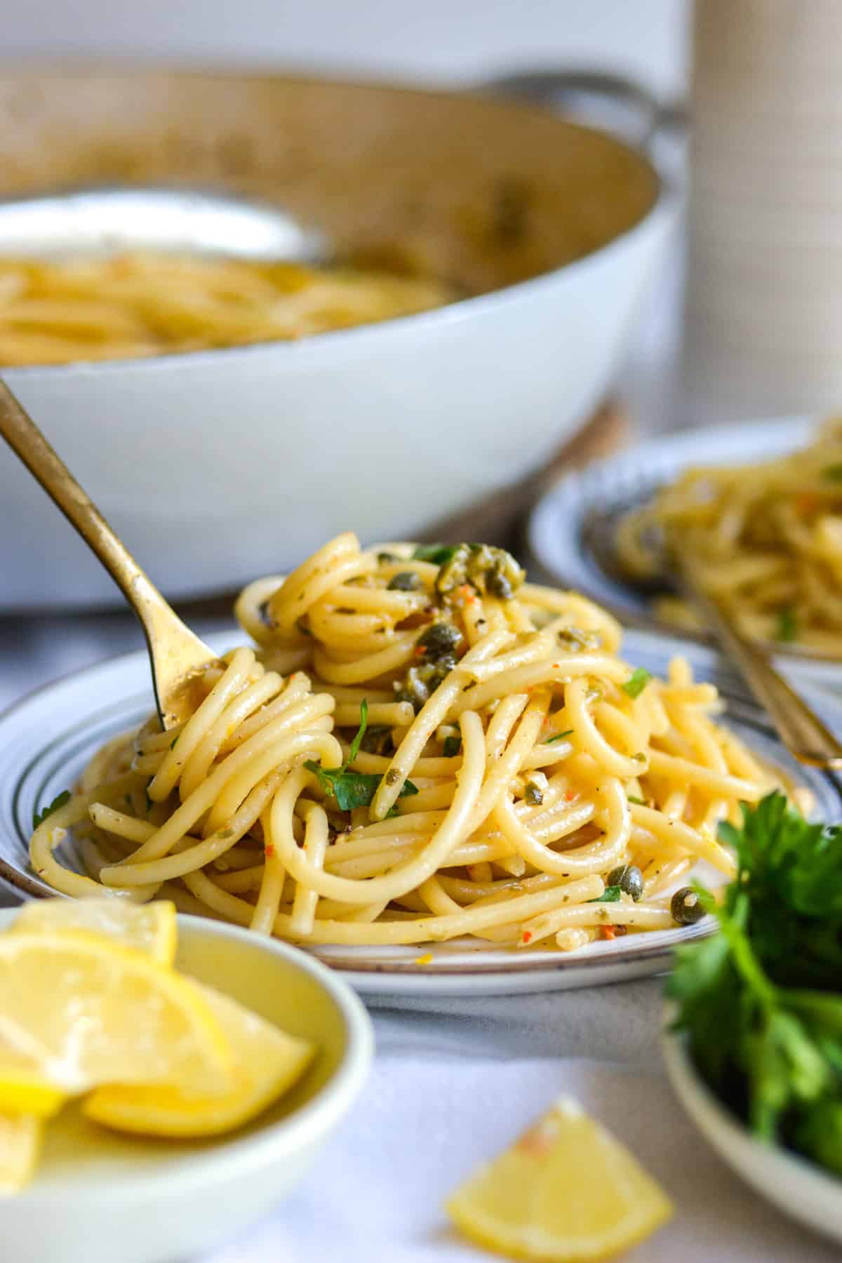 A plate of Vegan Lemon Caper Pasta with a fork in it.