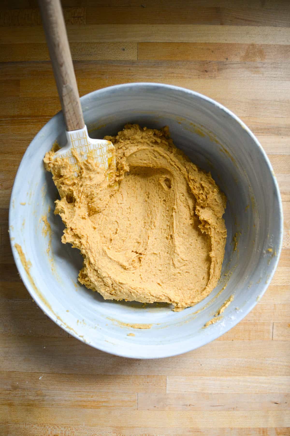 Cookie dough in a large mixing bowl with a rubber spatula.