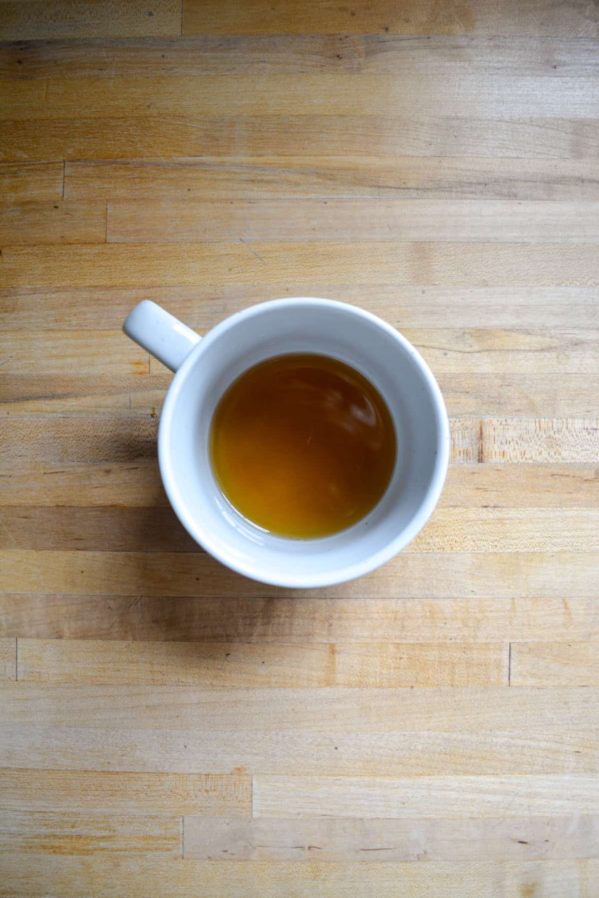 Maple syrup, bourbon and lemon juice in a mug.