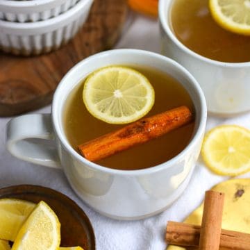 A bourbon hot Toddy in a white mug on a linen cloth.