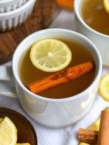 A bourbon hot Toddy in a white mug on a linen cloth.