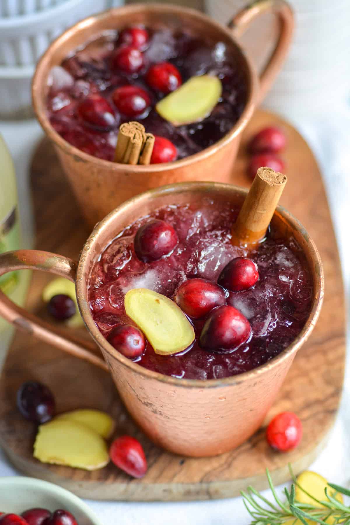 Cranberry Juice Mocktails in copper mugs on a small wooden board.